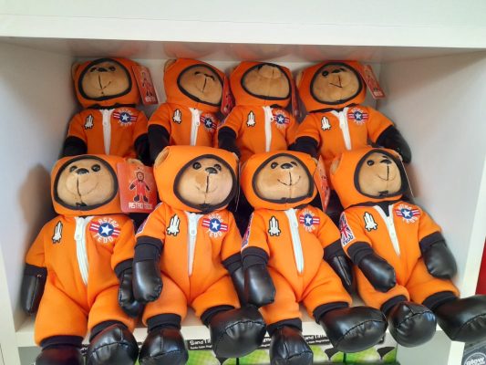 A row of teddy bears wearing orange astronaut jump suits.