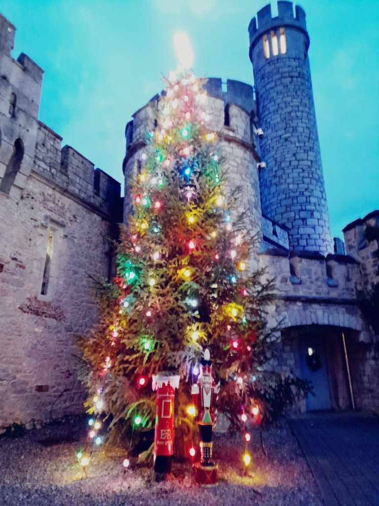 An enormous Christmas tree set in front of a medieval castle