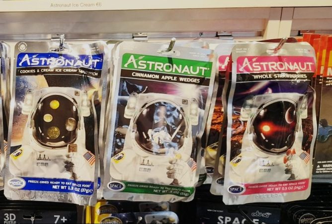 A photograph showing three freeze dried astronaut ice cream packets. There is a photo of an astronaut on each packet
