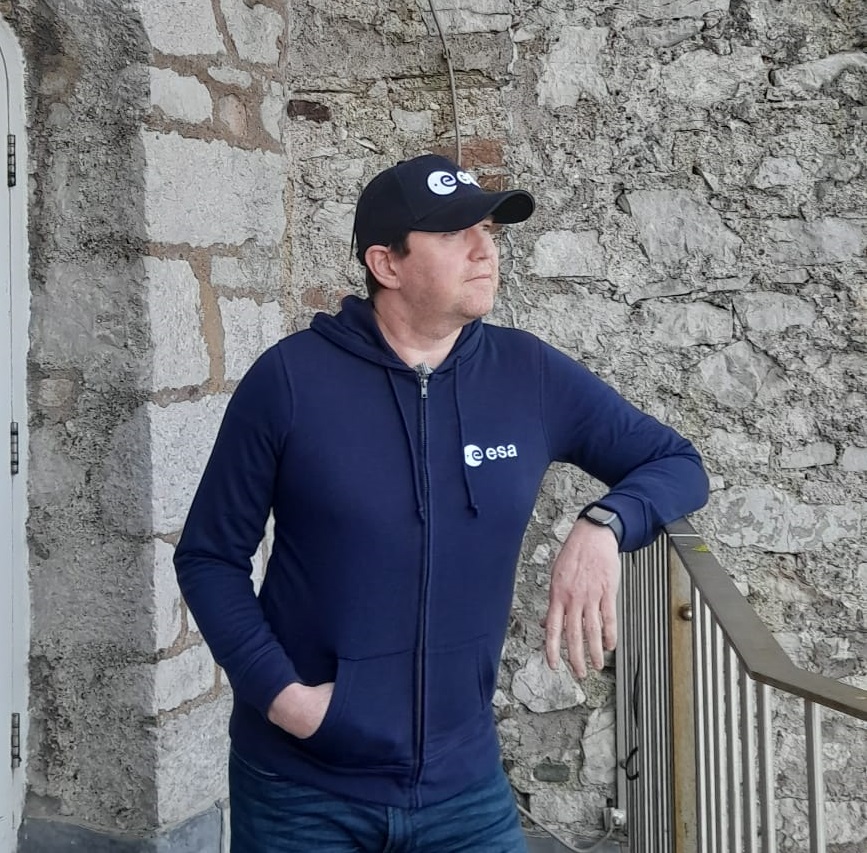A photo of a man wearing a navy ESA hoodie and a baseball cap