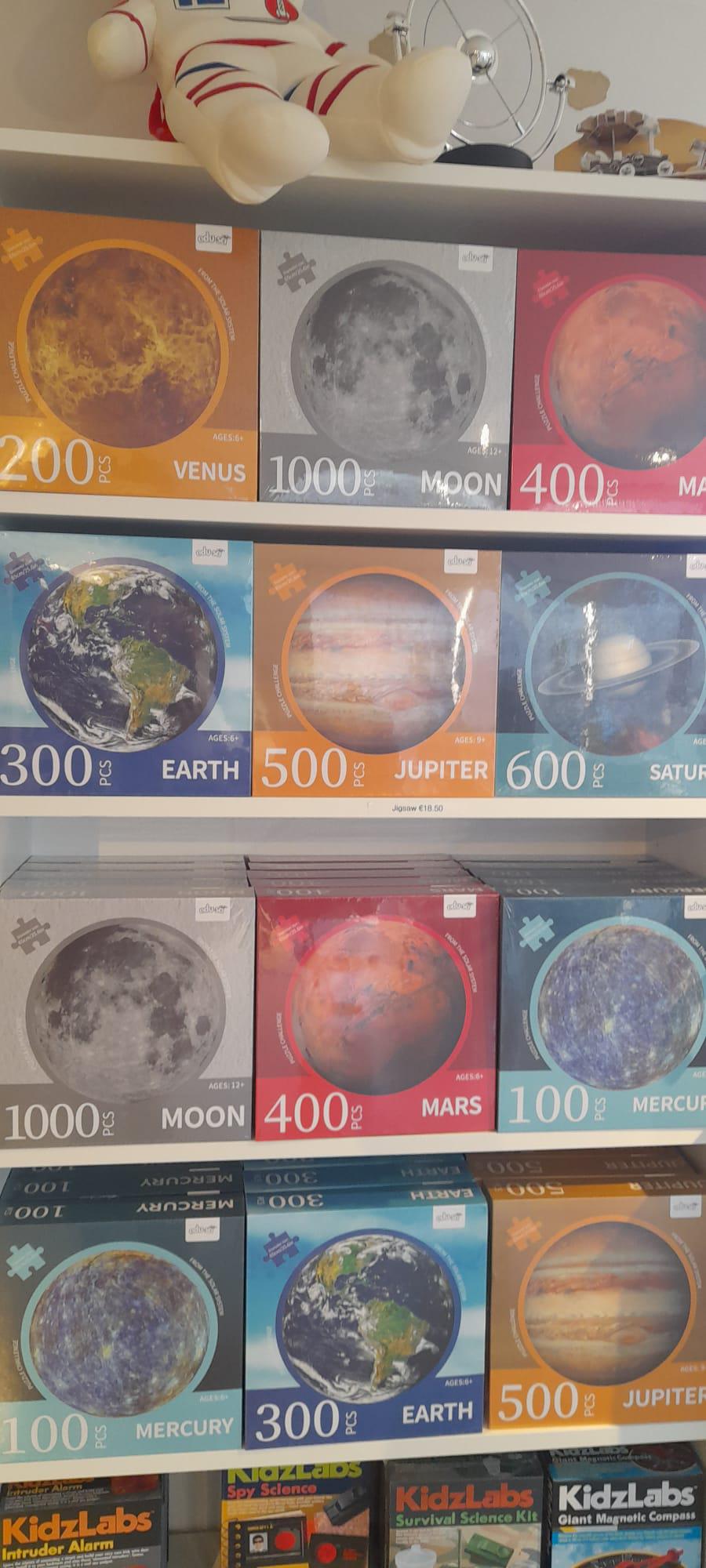 A selection of space-themed jigsaw puzzles in varying degrees of complexity. The photo shows the boxes for puzzles such as Venus, Mars, Jupiter, Saturn, Mercury, Earth and the Moon. Puzzles range in compelxity from 100 pieces to 1000.