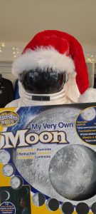 A toy moon being held in place by a model astronaut wearing a Santa hat